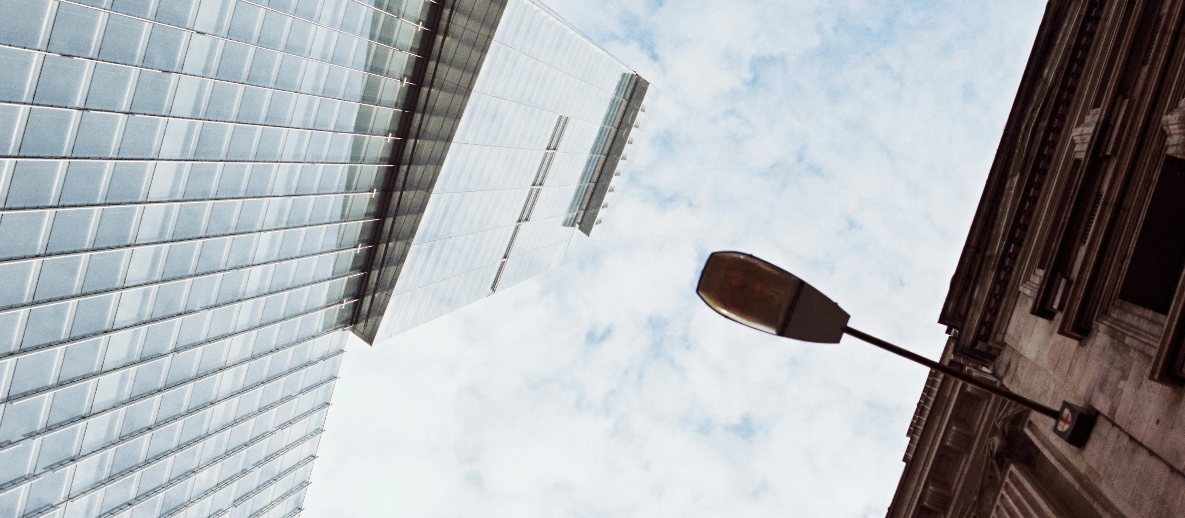 An image of two buildings when looking up. One modern and new and other legacy and established. Representing the two worlds of AlisAlpha